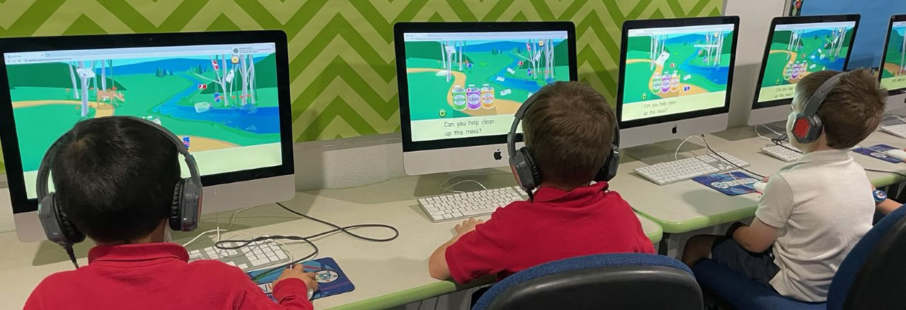 Three elementary students in the computer lab playing learning games