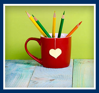Red coffee mug filled with colored pencils on a desk